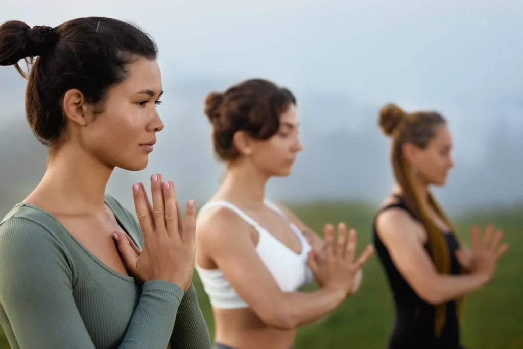 asian woman green wear meditating near blurring females foggy nature